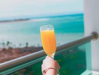 a person holding up a glass of orange juice at Hotel HBlue Malecón in La Paz
