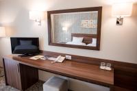 a hotel room with a desk and a mirror at Hotel Arnia in Iaşi
