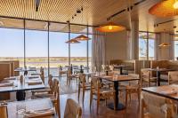 Un restaurante con mesas y sillas y grandes ventanales. en Monarto Safari Resort, en Monarto