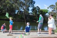a group of people standing on a dock fishing at Lorne Foreshore Caravan Park in Lorne