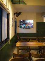 a restaurant with tables and chairs and a tv on the wall at Grihum Living Girls - FEMALE ONLY in Rānchī