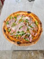 een pizza met ham en groenten op een tafel bij Vila OK2 in Costinesti