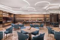 Un restaurante con sillas y mesas azules y un bar. en Crystal Hotel Guangzhou Huadu, en Huadu