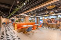 a restaurant with orange chairs and tables and windows at Shanghai Elong Hotel by the bund and Nanjing road Pedestrian street in Shanghai