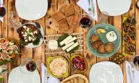 a wooden table topped with plates and bowls of food at Mimani Stone House Roshnik in Roshnik