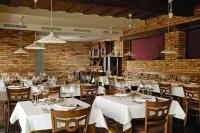 Un restaurante con mesas y sillas blancas con copas de vino. en Posestvo Pule Equestrian Estate, en Trebelno