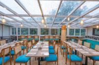 Un comedor con mesas y sillas y ventanas. en Excel Hotels & Resorts Mall Road Nainital, en Nainital