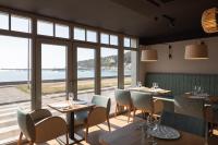 een restaurant met tafels en stoelen en uitzicht op de oceaan bij Hotel de la Plage in Erquy