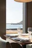 een tafel met wijnglazen en uitzicht op de oceaan bij Hotel de la Plage in Erquy