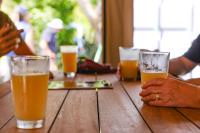 um grupo de pessoas sentadas numa mesa com copos de cerveja em Hot Water Beach TOP 10 Holiday Park em Hotwater Beach