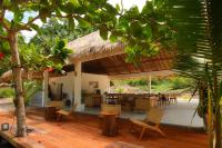 un patio con sedie, tavoli e tetto di paglia di Uma Resort Togean a Katupa