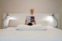 una persona tirada en una cama leyendo un libro en Aparthotel Los Girasoles, en Zaragoza