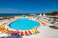 ein Swimmingpool mit Stühlen und Sonnenschirmen und das Meer in der Unterkunft Arena Grand Kazela Camping Homes in Medulin
