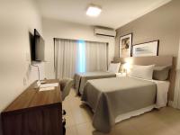 Una habitación de hotel con dos camas y un televisor. en Matiz Multi Suites, en Duque de Caxias