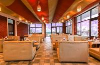 Hotel Holiday Hill Mcleodganj-Near to Dalai Lama Temple & Mall Road في دارامسالا: مطعم به طاولات وكراسي ونوافذ