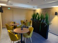 a waiting room with tables and chairs and plants at Le Billot in Bologne