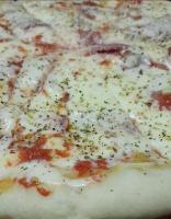 a close up of a pizza with cheese and herbs at Hospedaje Los Buenos Aires in Santa Ana