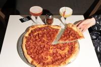 a person holding a slice of pepperoni pizza on a table at Hotel Ziggy On Sunset in Los Angeles