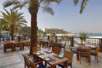a restaurant with tables and chairs and palm trees at DoubleTree by Hilton Resort & Spa Marjan Island in Ras al Khaimah