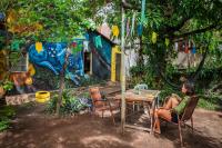 una mujer sentada en una mesa frente a una casa en MANGAMEL Hostel Pousada, en Lençóis