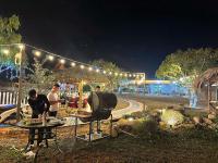 a group of people standing around a grill at night at Mely Farm Mường Lò in Văn Chấn