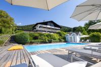 a house with a swimming pool and an umbrella at Hotel Garni Wurzer in Velden am Wörthersee