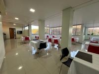 a dining room with white tables and chairs and windows at Benni Palace Hotel in Parauapebas