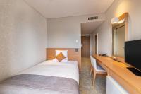 Una habitación de hotel con una cama, un escritorio y un televisor. en Art Hotel Niigata Station, en Niigata
