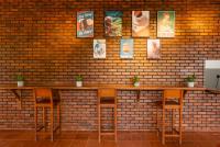 uma parede de tijolos com dois bancos de bar e quadros nela. em The Eight em Hikkaduwa