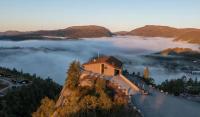 TjørhomFour bedroom holiday cottage in Sirdal的山顶上的房子，山谷里雾气弥漫。