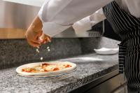 a chef is preparing a pizza on a counter at Regnum Banya Thermal Hotel in Banya