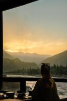una mujer sentada en una mesa mirando a las montañas en Cascade Resorts Ghawari, Gilgit-Baltistan, en Kuru