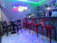 eine Bar mit roten Stühlen und einem Leuchtschild in der Unterkunft Niji Luxury studio apartments in Amasaman