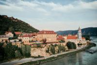 a town on a hill next to a river at Hotel Schloss Dürnstein in Dürnstein