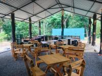 a group of wooden tables and chairs under a pavilion at Cinnamon Leaf Leisure Resort in Badureliya