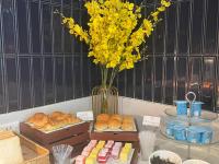 花都柏高酒店(广州白云机场莲塘地铁站店)的一张桌子,上面有面包和黄色花瓶