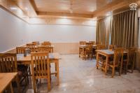 um restaurante vazio com mesas e cadeiras de madeira em the pahadi ghar em Gushaini