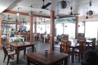 バルカラにあるHillview Beach Resortの木製のテーブルと椅子のあるレストランと、人が座っているレストラン