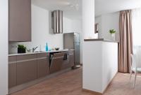 a kitchen with brown cabinets and a stainless steel refrigerator at Ténéo Apparthotel Talence Arthena in Talence