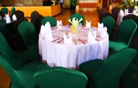 a table with a white table cloth and green chairs at Urban Park Suites Hotel in Kigali