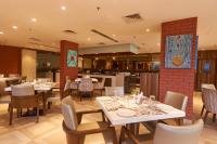 uma sala de jantar com mesas e cadeiras brancas em Tania President Inn em Shirdi