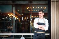 Een man staat met zijn armen over elkaar voor een raam. bij Hotel Manoir Victoria in Québec