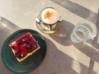 a piece of cake on a green plate next to a drink at Omalia Village in Áno Khóra