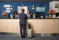 un hombre parado en un mostrador con una mujer en Holiday Inn Express Geneva Airport by IHG, en Ginebra