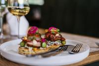 une assiette de nourriture sur une table avec un verre de vin dans l'établissement Menlyn Boutique Hotel, à Pretoria