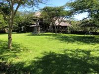 a yard with a house with trees and a grassy field at Isalaasha Bush Camp in Mau Narok