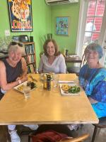 tres mujeres sentadas en una mesa con platos de comida en The Reserve Retreat, en Sarasota