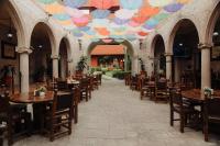un restaurante con mesas y sillas y un techo con sombrillas en Hotel Mesón de los Cristeros, 