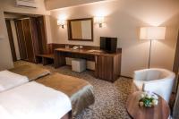 a hotel room with two beds and a desk and a television at Hotel Arnia in Iaşi