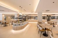 Un restaurante con mesas y sillas y un bar. en Hotel RH Arena - Todo Incluido, en Gandía
